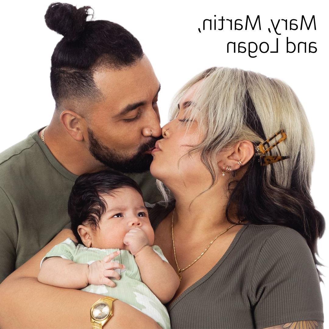 parents kissing while holding their baby